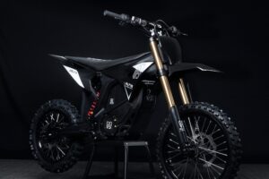 Altis Delta electric dirt bike performing a high jump on a rugged off-road trail in Europe.