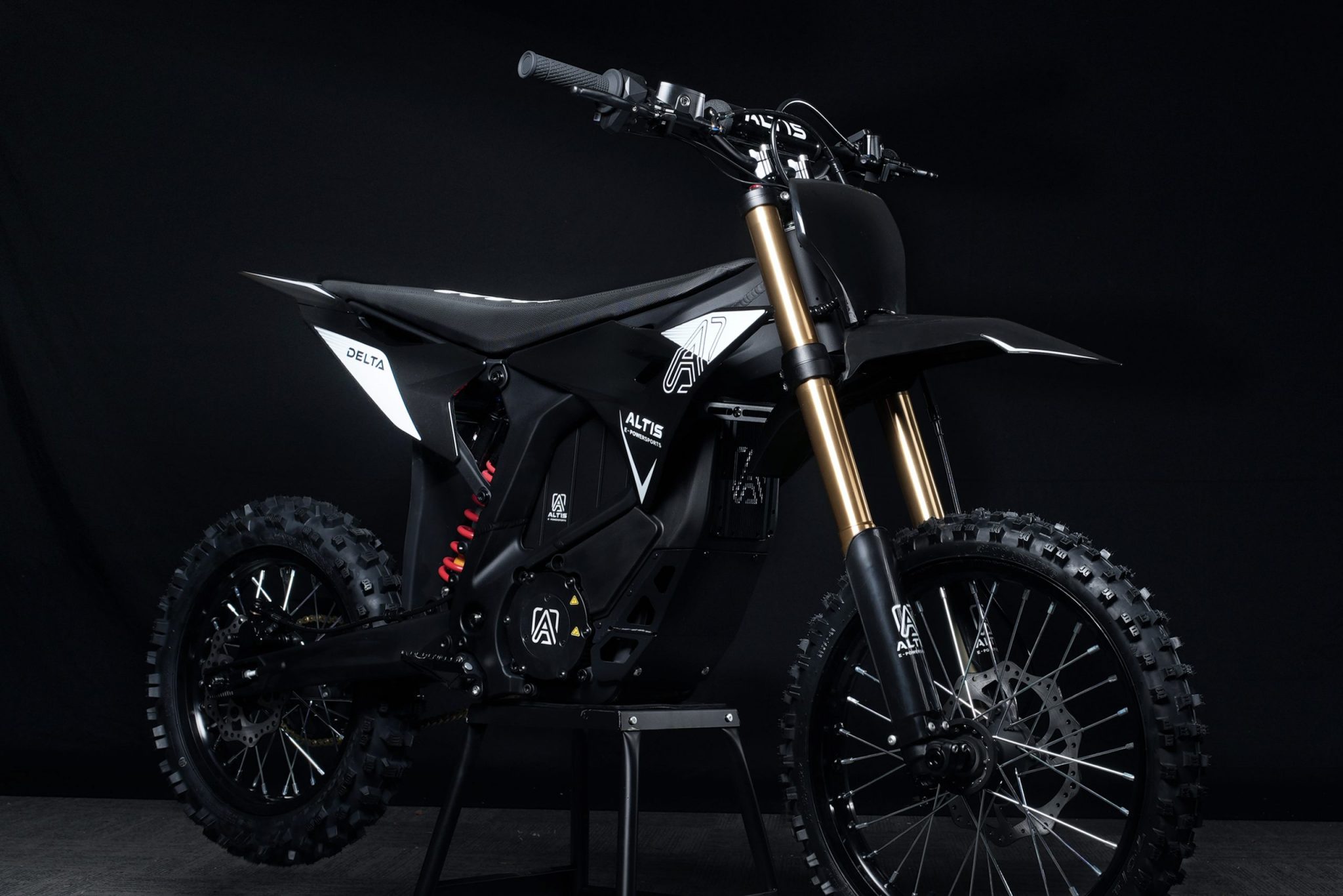 Altis Delta electric dirt bike performing a high jump on a rugged off-road trail in Europe.